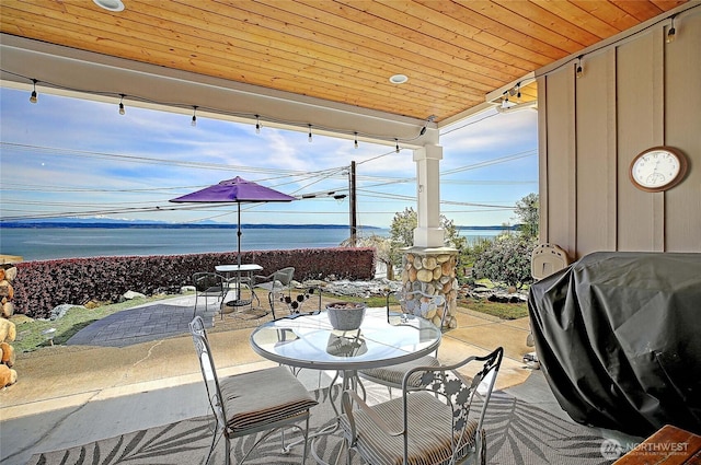 view of patio with area for grilling, outdoor dining area, and a water view