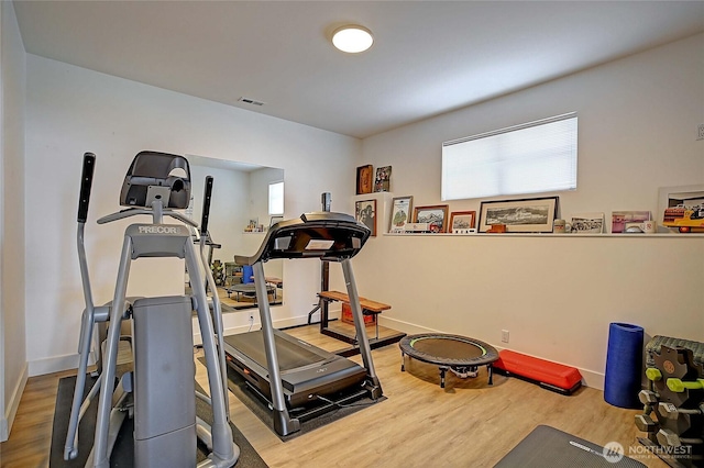 exercise room with baseboards, wood finished floors, and visible vents