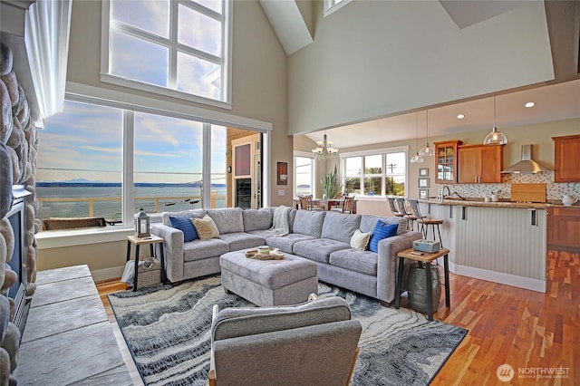 living area with a high ceiling, a notable chandelier, and light wood-style flooring