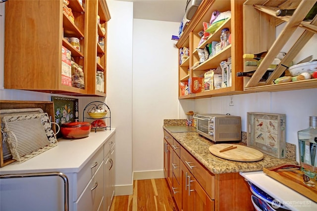 interior space featuring a toaster, baseboards, and light wood-style floors