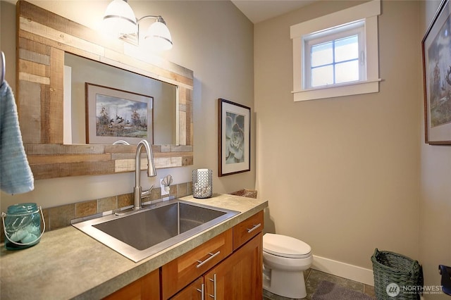 bathroom featuring baseboards, toilet, and vanity