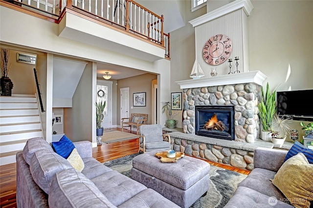 living room with baseboards, wood finished floors, a high ceiling, stairs, and a fireplace