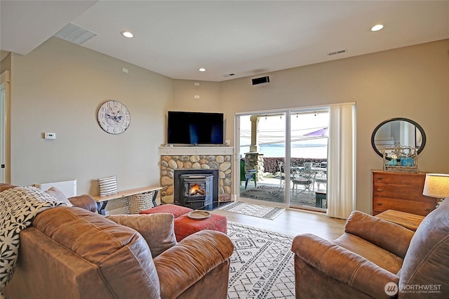 living room with recessed lighting, a stone fireplace, visible vents, and wood finished floors
