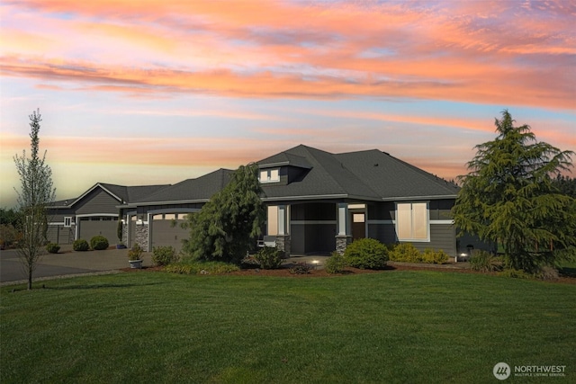 view of front of home featuring a front lawn, driveway, stone siding, and a garage