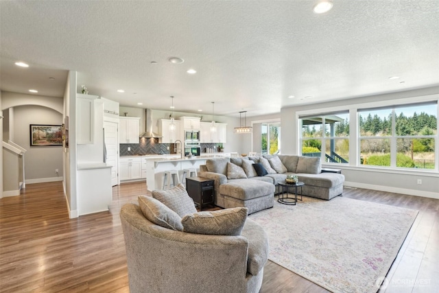 living area with a textured ceiling, light wood finished floors, and baseboards