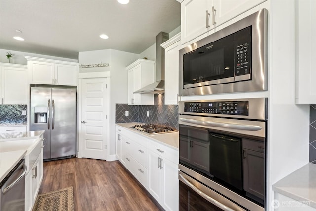 kitchen featuring white cabinets, light countertops, appliances with stainless steel finishes, and wall chimney range hood