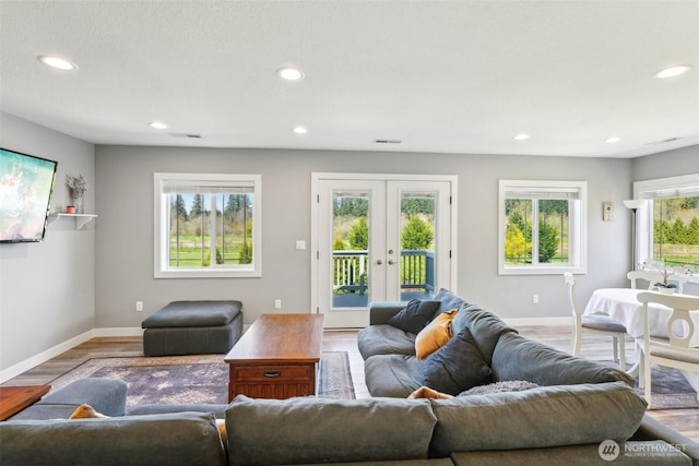 living area with recessed lighting, light wood-style floors, baseboards, and french doors