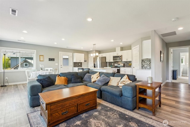 living room featuring baseboards, wood finished floors, visible vents, and recessed lighting