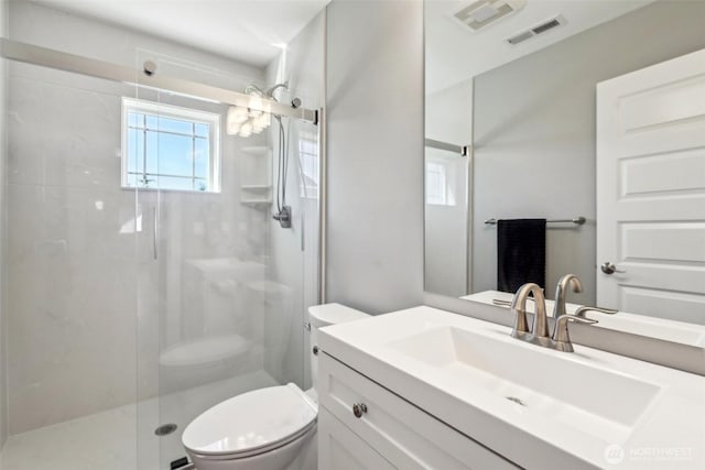 bathroom featuring a shower stall, toilet, vanity, and visible vents