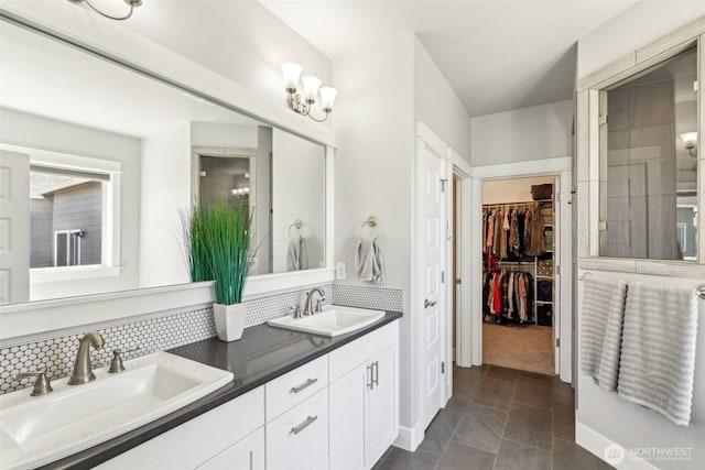 full bath featuring a walk in closet, tasteful backsplash, double vanity, and a sink