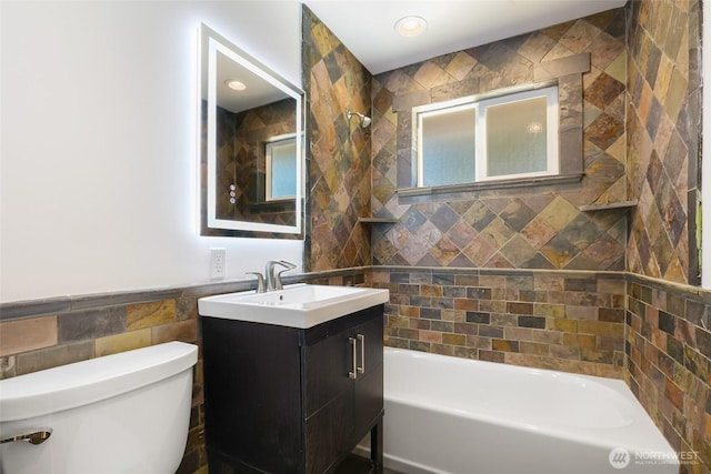 full bathroom with toilet, tile walls, and vanity