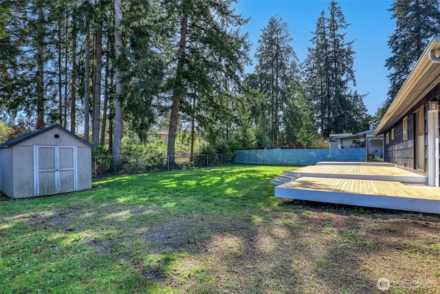 view of yard with a shed, a fenced backyard, a deck, and an outdoor structure