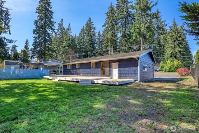 back of property featuring fence, a deck, and a lawn