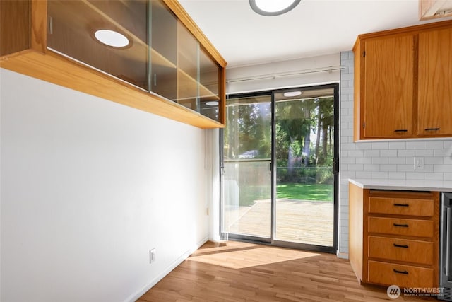 doorway to outside with wine cooler, light wood finished floors, and baseboards