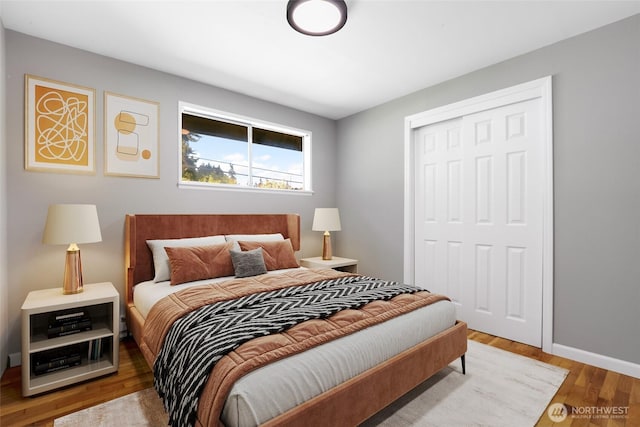 bedroom with a closet, baseboards, and wood finished floors