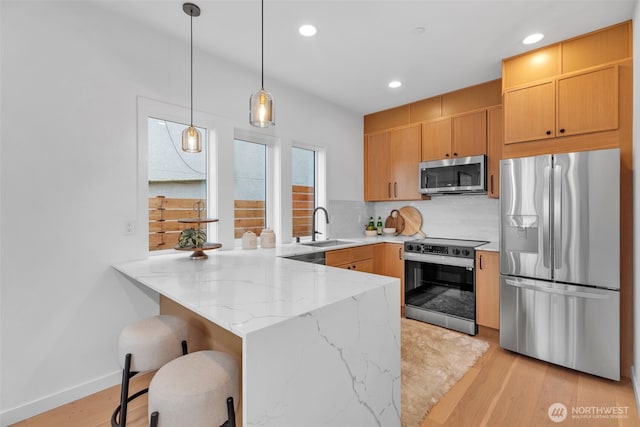431 19th Ave E, Seattle, WA 98112 - kitchen featuring appliances with stainless steel finishes, a peninsula, a sink, light stone countertops, and recessed lighting