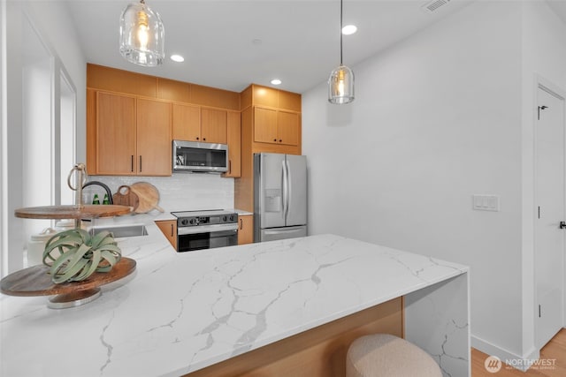 431 19th Ave E, Seattle, WA 98112 - kitchen featuring appliances with stainless steel finishes, a sink, tasteful backsplash, light stone countertops, and a peninsula