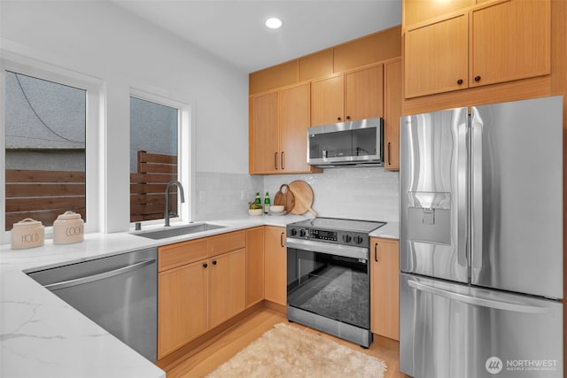 431 19th Ave E, Seattle, WA 98112 - kitchen with appliances with stainless steel finishes, a sink, light stone countertops, tasteful backsplash, and light wood-style flooring