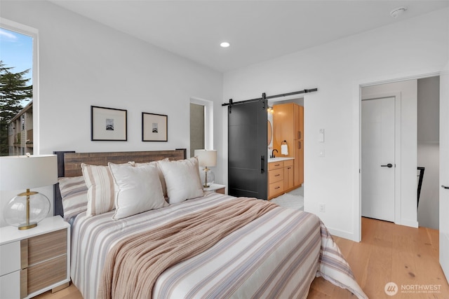 431 19th Ave E, Seattle, WA 98112 - bedroom with a barn door, light wood-style flooring, a sink, recessed lighting, and connected bathroom