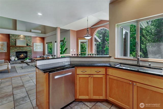 kitchen with a healthy amount of sunlight, dark stone countertops, a sink, and dishwasher