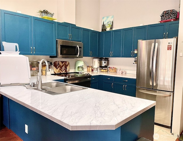 kitchen featuring appliances with stainless steel finishes, blue cabinetry, and a sink