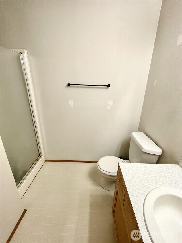 full bathroom featuring vanity, tile patterned floors, toilet, a stall shower, and baseboards