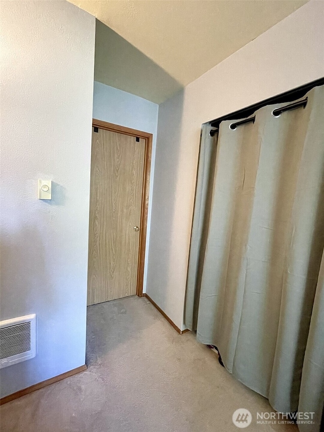 hall with visible vents, light carpet, and baseboards