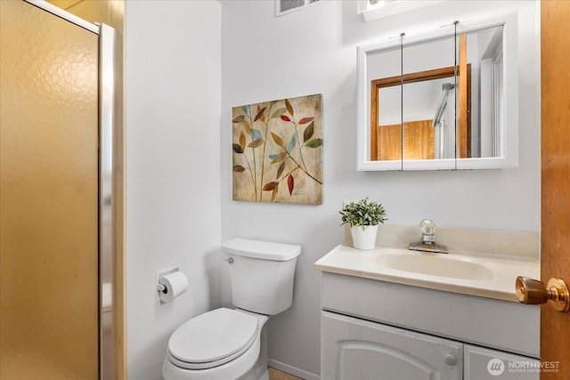 bathroom with vanity, a shower stall, and toilet