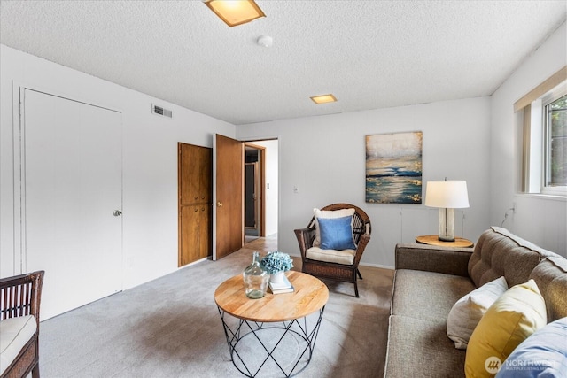 living area with light colored carpet, a textured ceiling, and visible vents