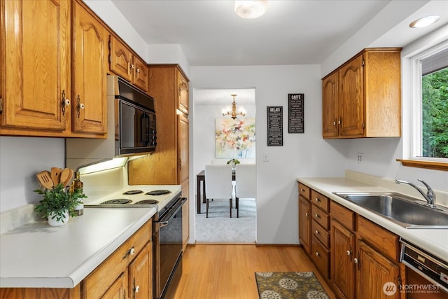 kitchen featuring electric range, black microwave, a sink, brown cabinetry, and light wood-type flooring