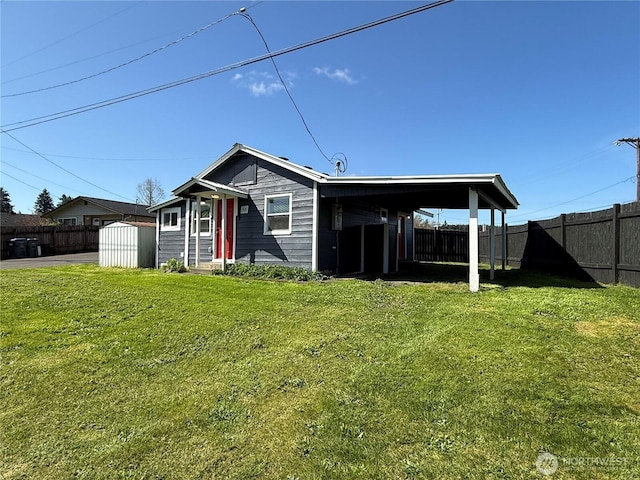 back of property with a storage shed, fence, an outdoor structure, and a lawn