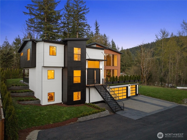 contemporary home with a garage, stairway, and a lawn