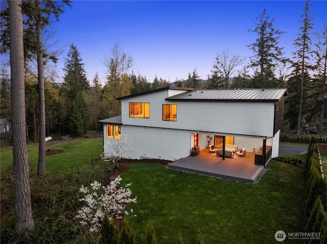 back of house featuring a patio, metal roof, and a lawn