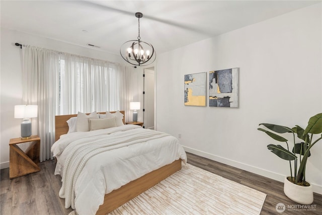 bedroom with wood finished floors, baseboards, and a notable chandelier
