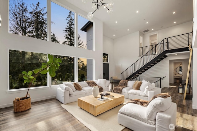 living area featuring a notable chandelier, stairway, recessed lighting, a towering ceiling, and wood finished floors