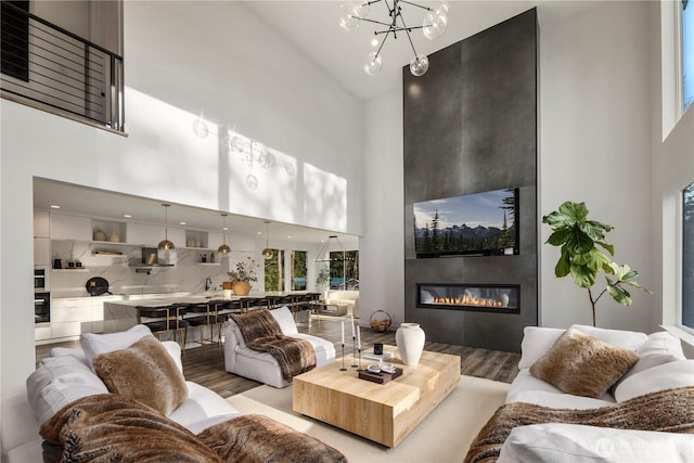 living area with high vaulted ceiling, a large fireplace, and wood finished floors