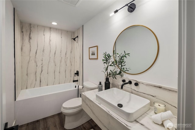 bathroom featuring shower / tub combination, toilet, visible vents, a sink, and wood finished floors