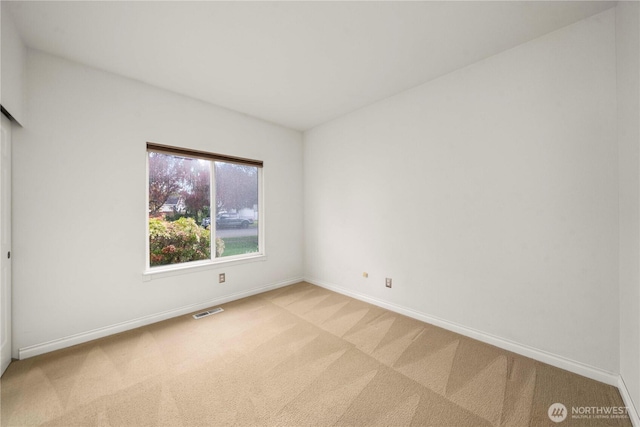 unfurnished room with light carpet, visible vents, and baseboards