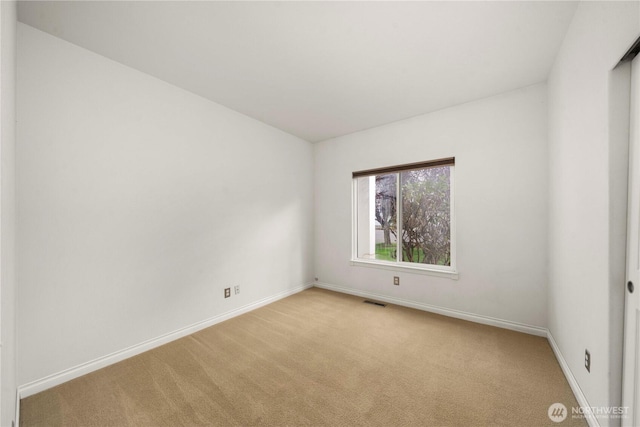 spare room with baseboards, visible vents, and light colored carpet