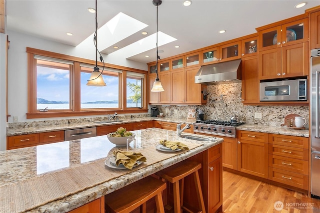 3193 Northshore Rd, Bellingham, WA 98226 - kitchen with brown cabinetry, a skylight, appliances with stainless steel finishes, a sink, and under cabinet range hood