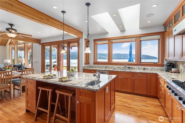 3193 Northshore Rd, Bellingham, WA 98226 - kitchen with light stone countertops, glass insert cabinets, brown cabinets, a sink, and light wood finished floors
