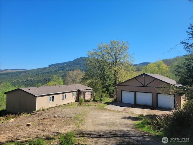 view of front of property featuring a view of trees, an outbuilding, a mountain view, and a garage