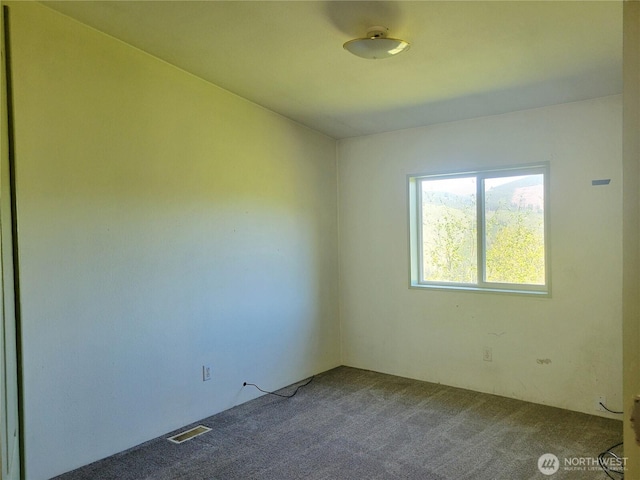 empty room featuring dark carpet and visible vents