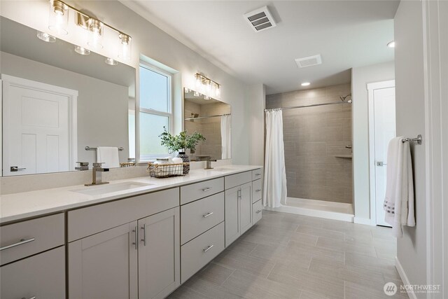 3009 Oleander Ln, Blaine, WA 98230 - bathroom with visible vents, a sink, double vanity, and tiled shower
