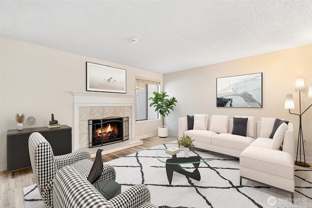 1555 Union Ave NE Unit 27, Renton, WA 98059 - living room with wood finished floors, a tiled fireplace, baseboards, and a textured ceiling