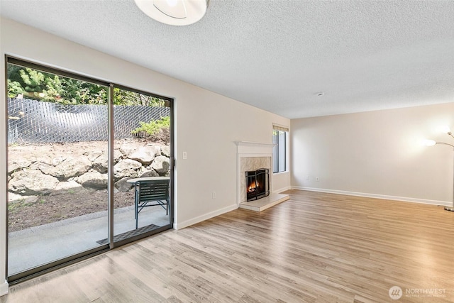 1555 Union Ave NE Unit 27, Renton, WA 98059 - unfurnished living room with a textured ceiling, light wood-type flooring, a high end fireplace, and baseboards