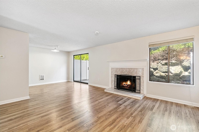 1555 Union Ave NE Unit 27, Renton, WA 98059 - unfurnished living room with wood finished floors, a tiled fireplace, baseboards, and a textured ceiling