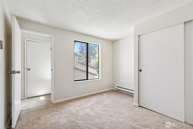 1555 Union Ave NE Unit 27, Renton, WA 98059 - unfurnished bedroom featuring a baseboard heating unit, carpet, a closet, and a textured ceiling