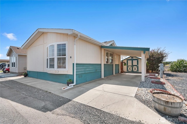 view of side of property featuring concrete driveway, a carport, an outdoor structure, and a storage unit