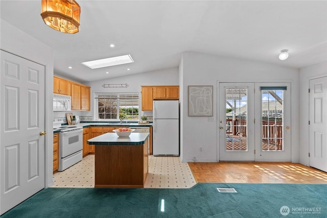 kitchen with vaulted ceiling with skylight, white appliances, visible vents, recessed lighting, and a center island